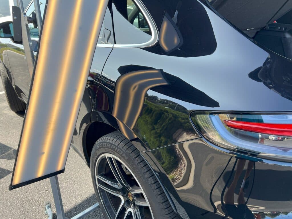 PDR technician inspecting hail damage on vehicle